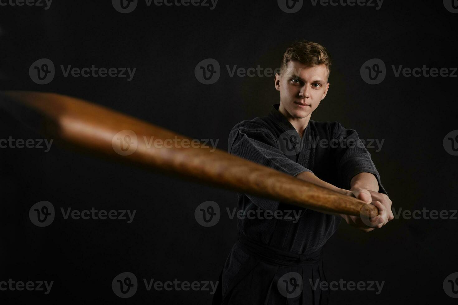 kendo gurú vistiendo en un tradicional japonés kimono es practicando marcial Arte con el shinai bambú espada en contra un negro estudio antecedentes. foto