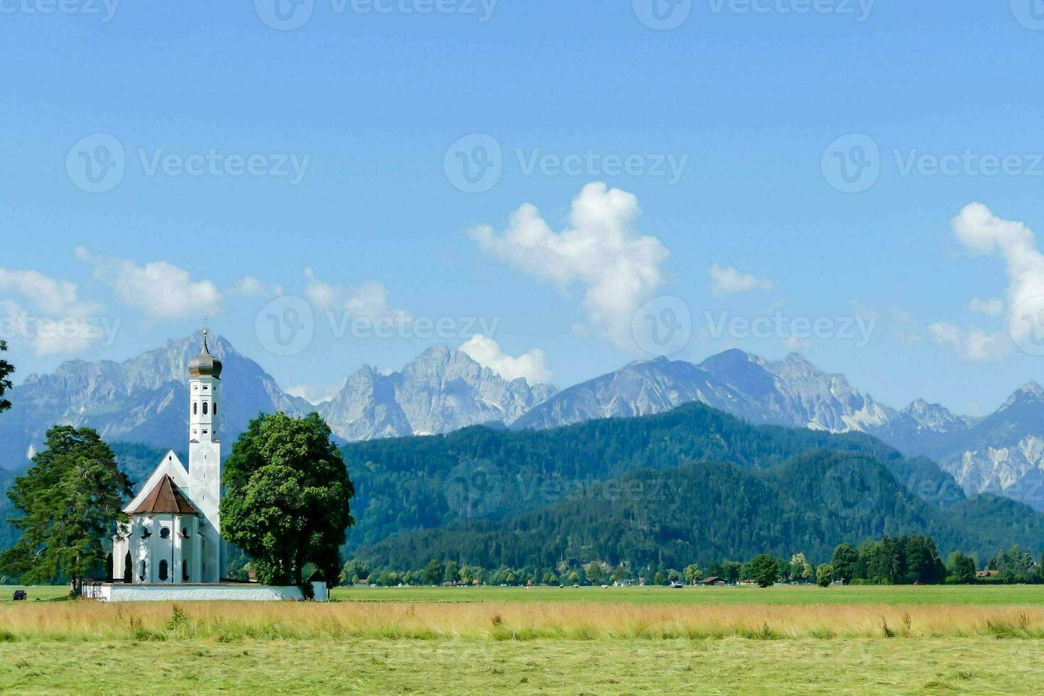 a church in the middle of a field with mountains in the background photo
