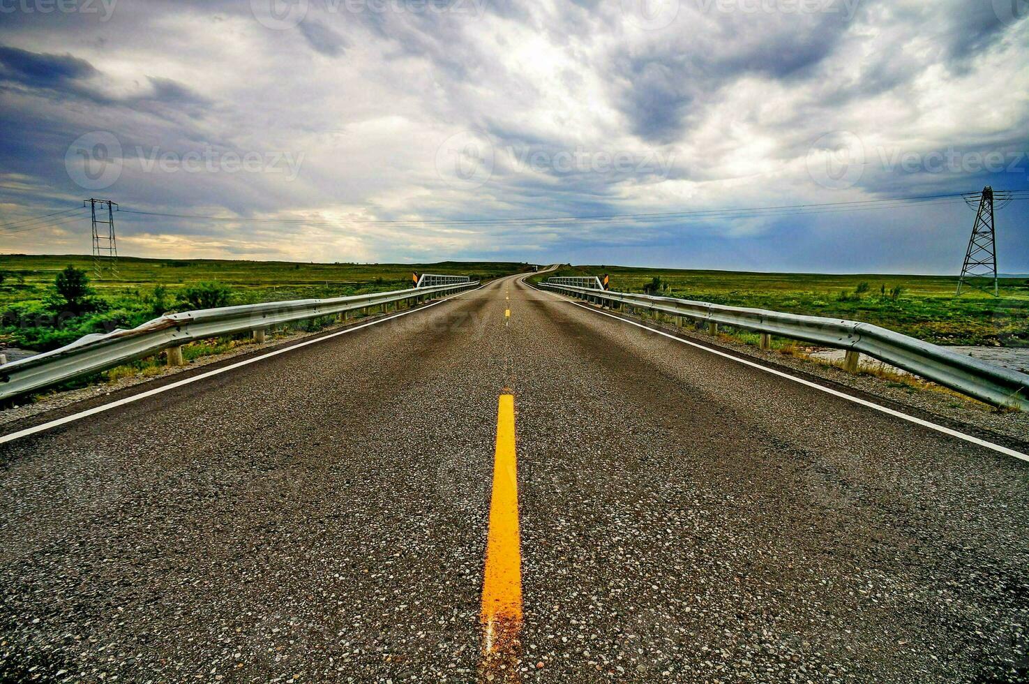 a long empty road under a cloudy sky photo