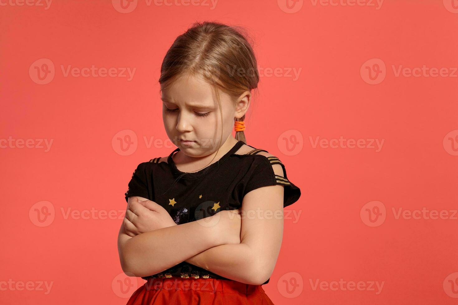 Close-up shot of a charming blonde little lady in a combined dress posing against a pink background. photo