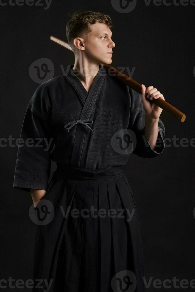 kendo gurú vistiendo en un tradicional japonés kimono es practicando marcial Arte con el shinai bambú espada en contra un negro estudio antecedentes. foto