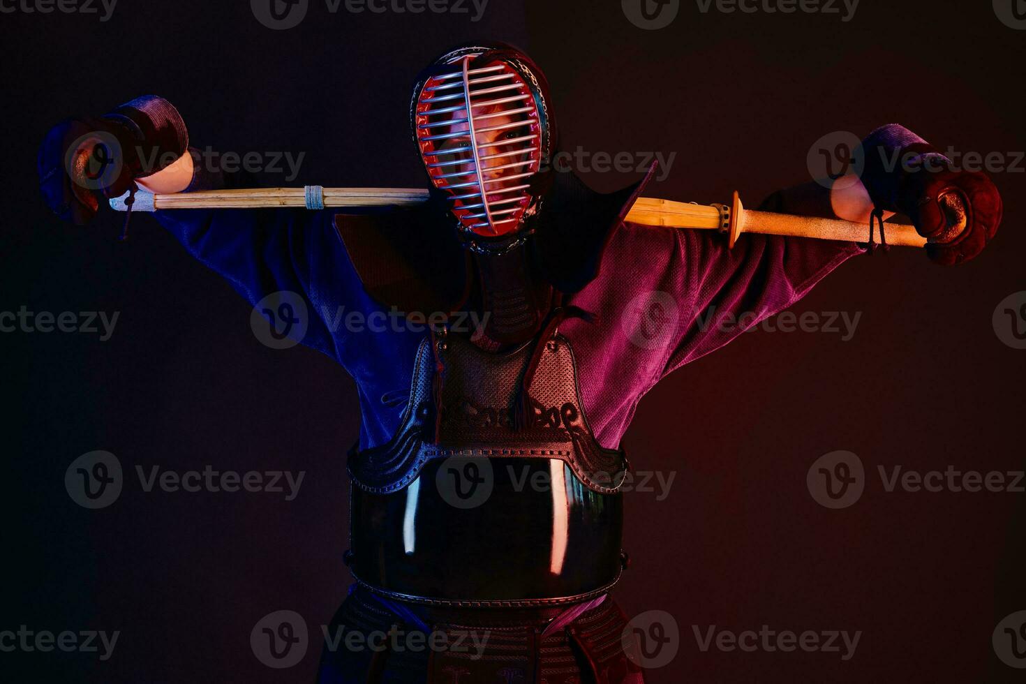 Close up shot, Kendo fighter wearing in an armor, traditional kimono, helmet practicing martial art with shinai bamboo sword, black background. photo