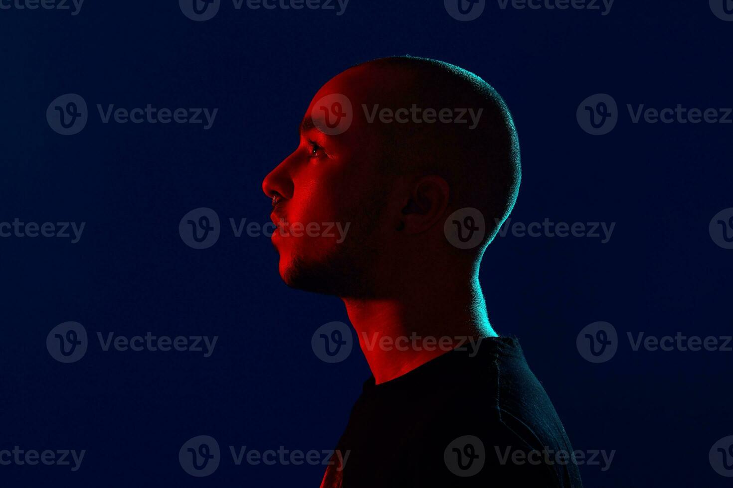 Studio shot of a young tattoed bald man posing against a blue background. 90s style. photo