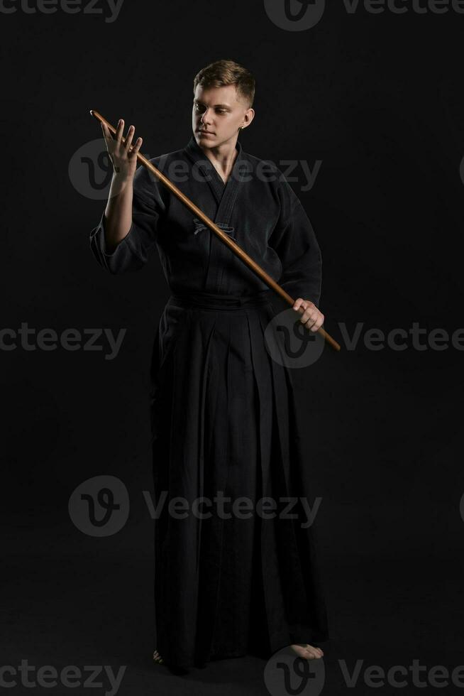 kendo gurú vistiendo en un tradicional japonés kimono es practicando marcial Arte con el shinai bambú espada en contra un negro estudio antecedentes. foto