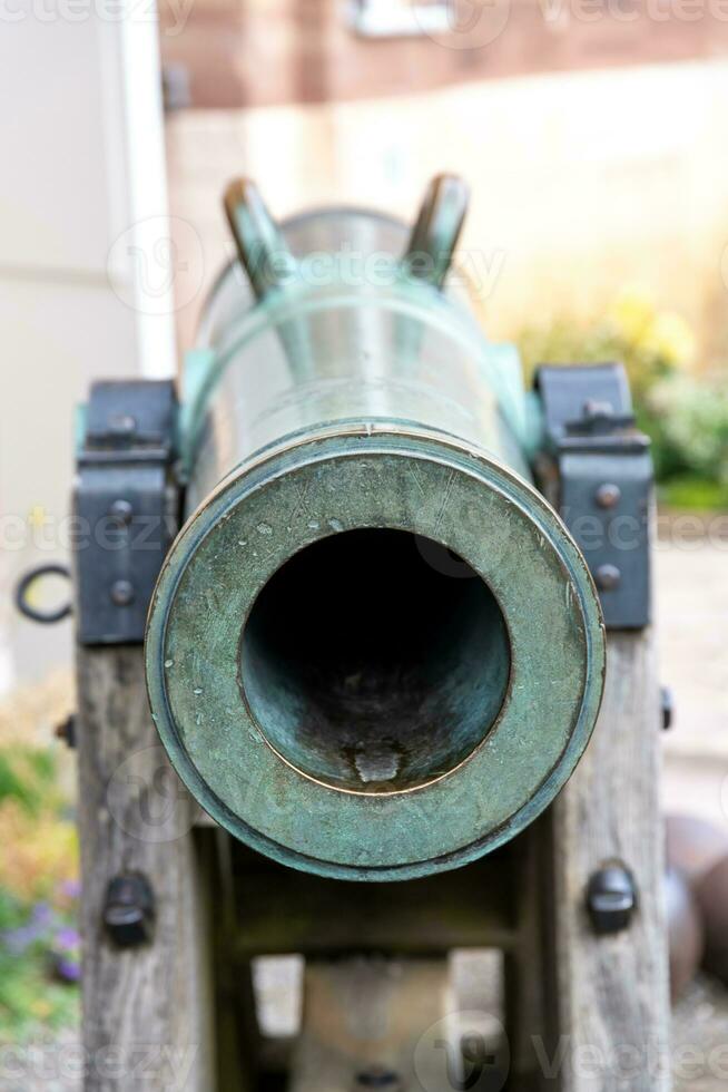 un pistola barril desde el frente, el cámara mira abajo el barril. el pistola carro es además hecho de madera y metal. usted lata claramente ver verde corrosión en el metal foto