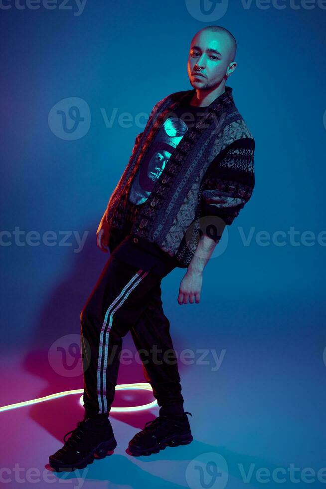 Studio shot of a young tattoed bald man posing against a colorful background. 90s style. photo