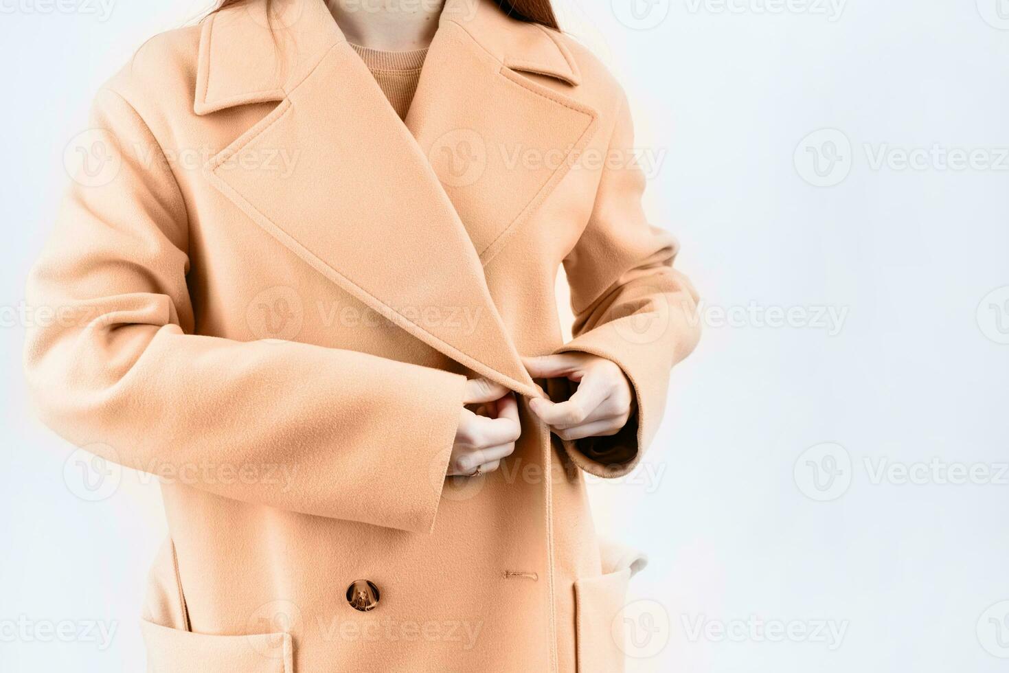 Color of the year 2024, Peach Fuzz.  closeup woman wearing beige pastel coat in white background photo