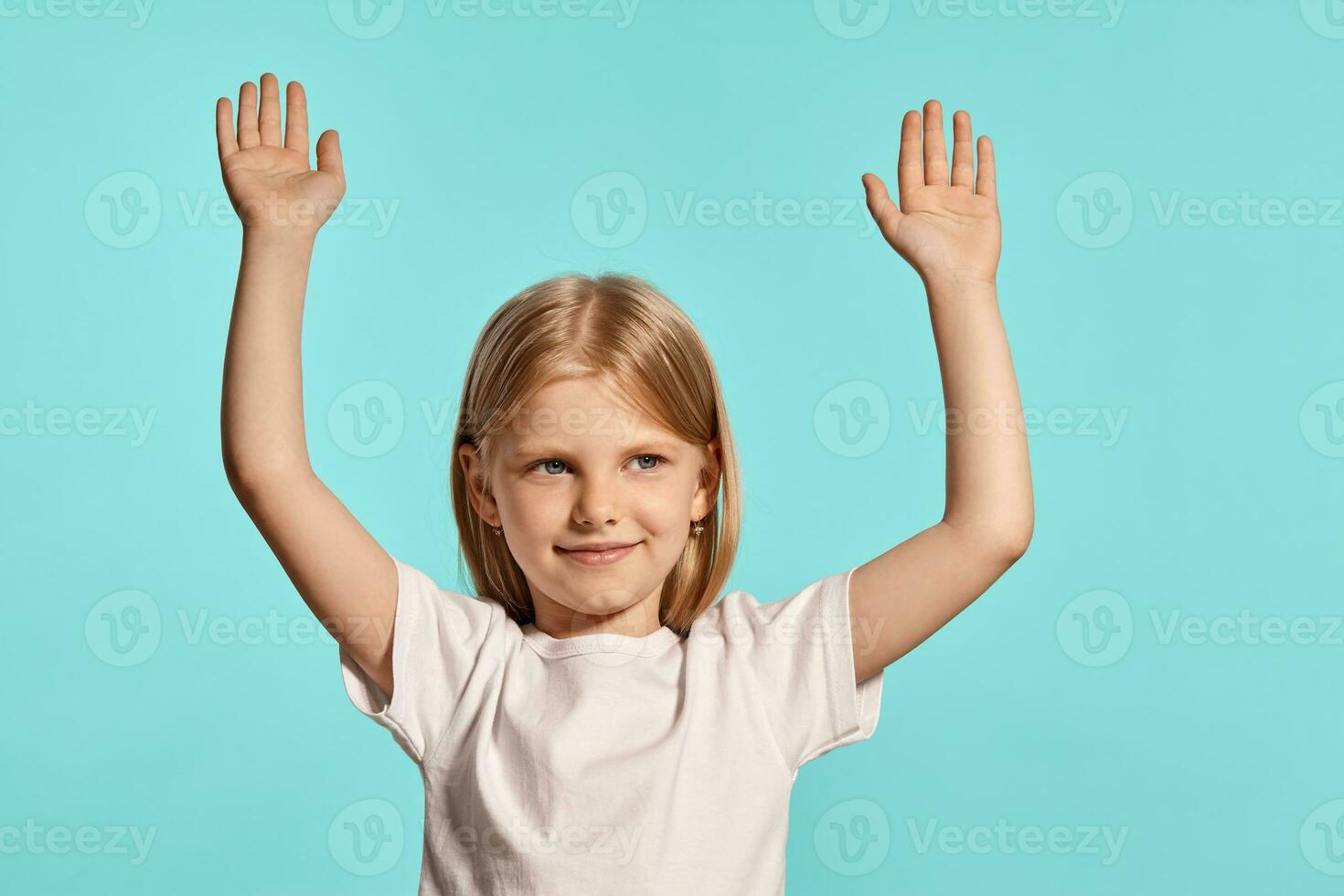 Close-up studio shot of a lovely blonde little girl in a white t-shirt posing against a blue background. photo