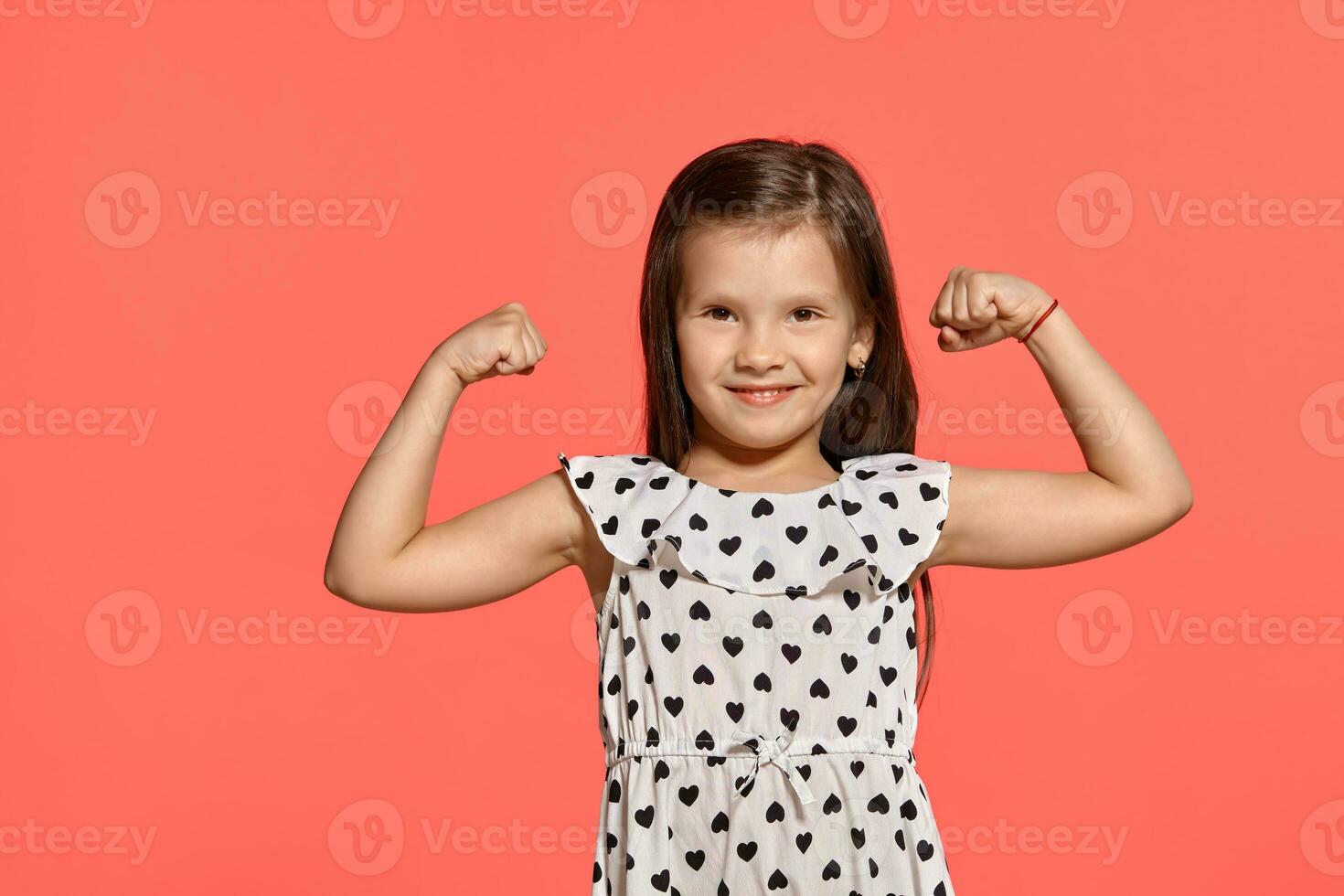 Close-up studio shot of beautiful brunette little girl posing against a pink background. photo