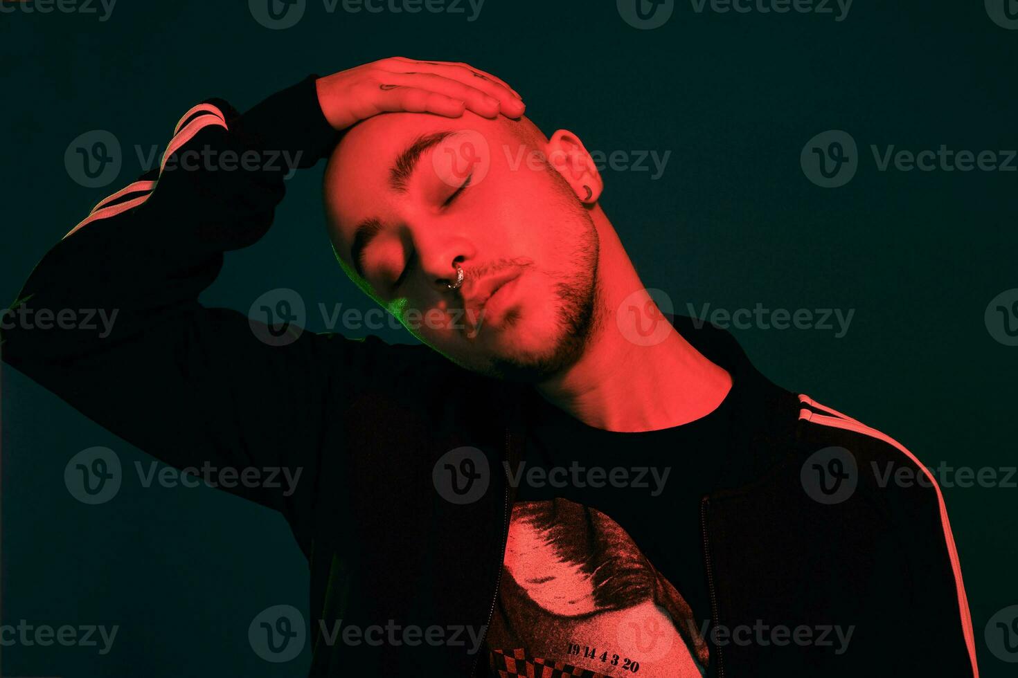 Studio shot of a young tattoed bald man posing against a colorful background. 90s style. photo