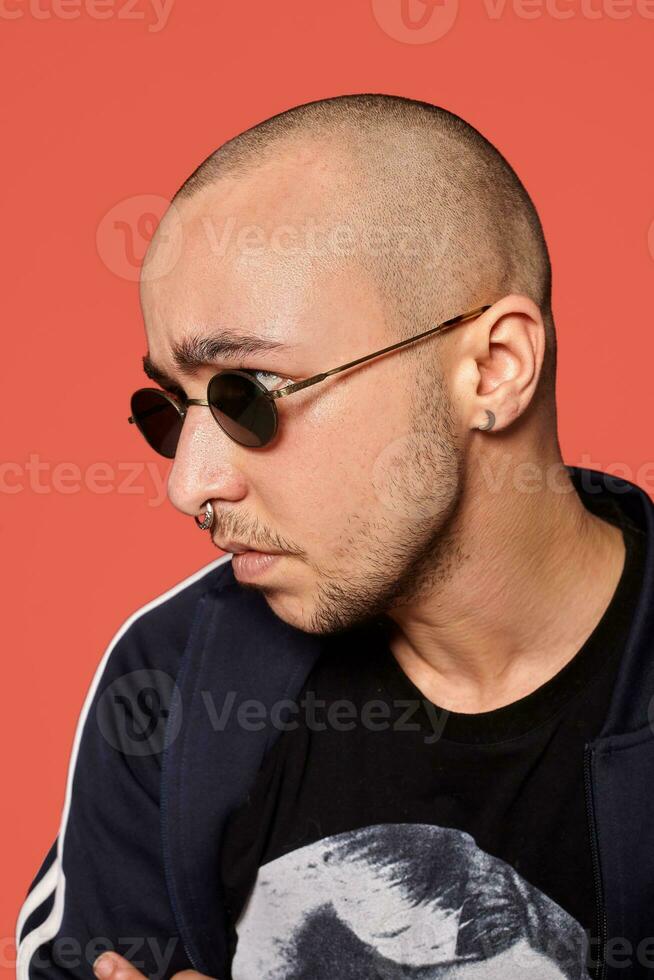 estudio Disparo de un joven tatuado calvo hombre posando en contra un rosado antecedentes. 90s estilo. foto