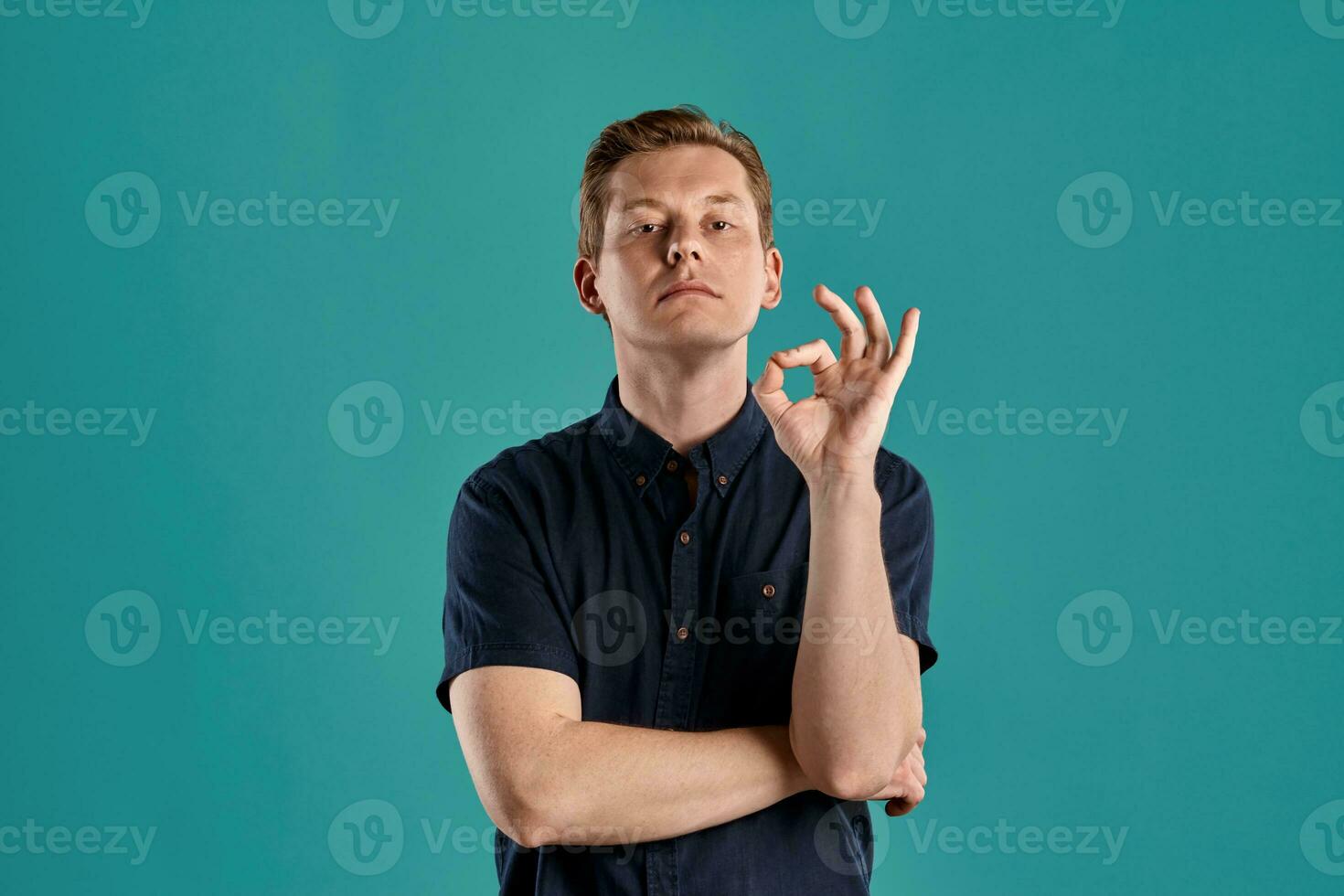 Close-up portrait of a ginger guy in navy t-shirt posing on blue background. Sincere emotions. photo