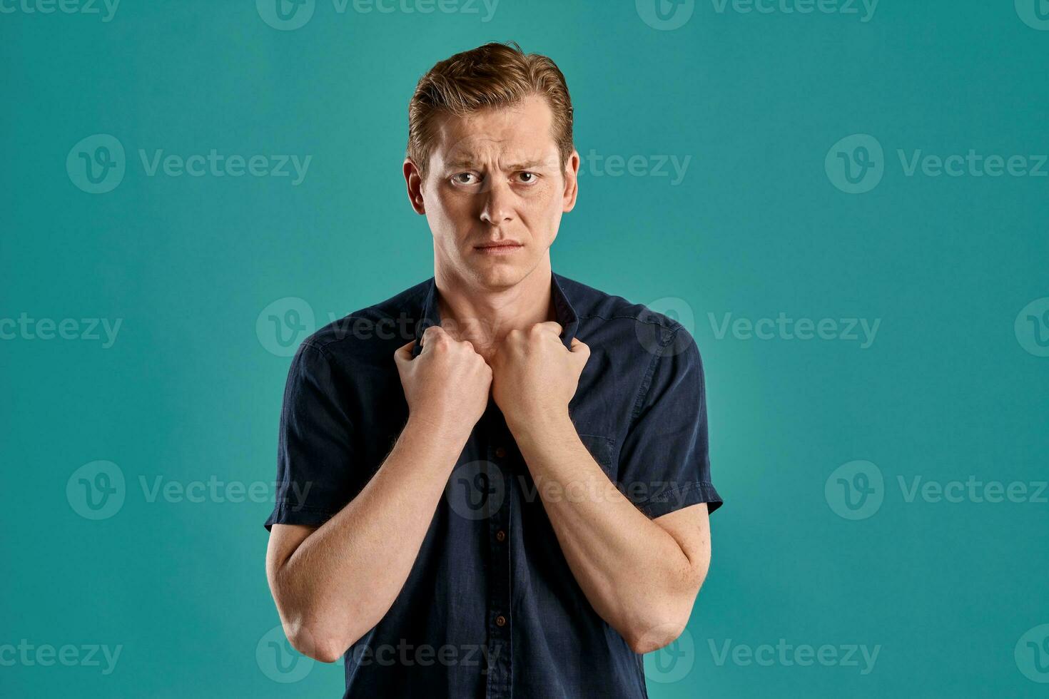 Close-up portrait of a ginger guy in navy t-shirt posing on blue background. Sincere emotions. photo