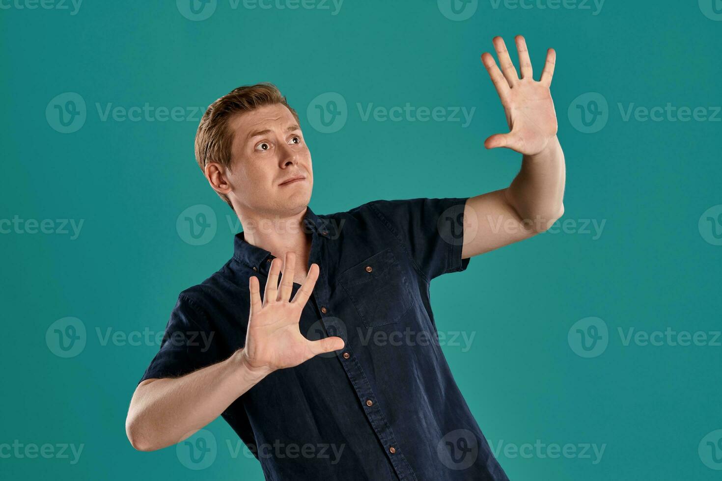 Close-up portrait of a ginger guy in navy t-shirt posing on blue background. Sincere emotions. photo