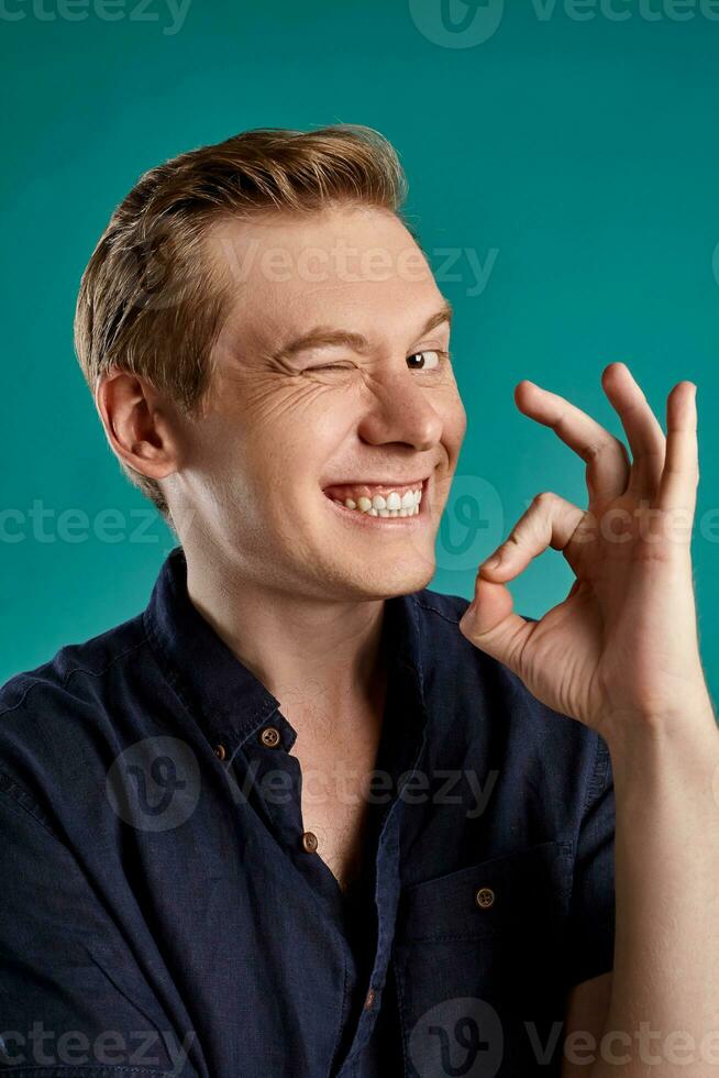 Close-up portrait of a ginger guy in navy t-shirt posing on blue background. Sincere emotions. photo