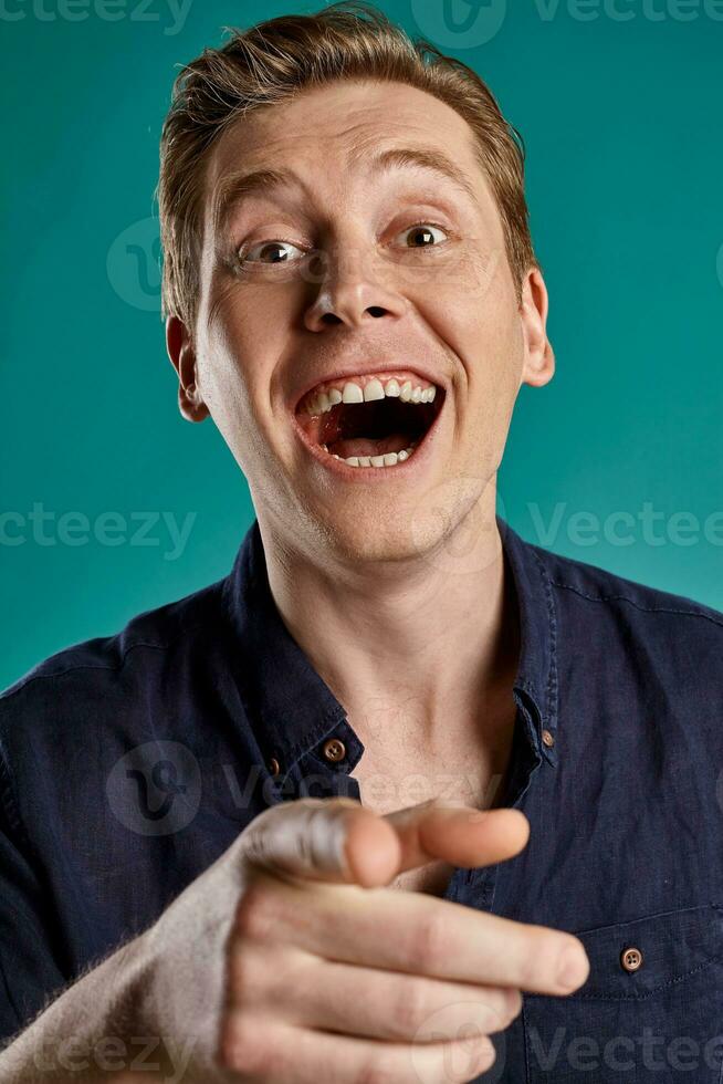 Close-up portrait of a ginger guy in navy t-shirt posing on blue background. Sincere emotions. photo