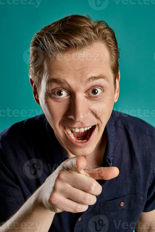 Close-up portrait of a ginger guy in navy t-shirt posing on blue background. Sincere emotions. photo