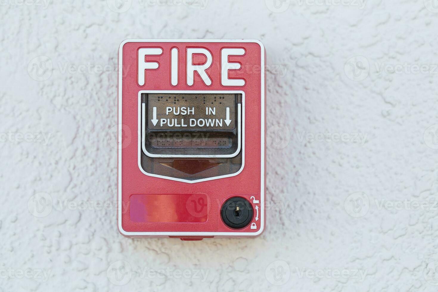 Red fire alarm switch at cement wall photo