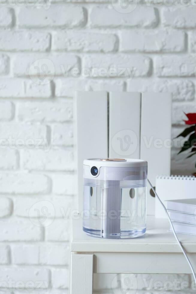 Modern air humidifier on table in living room or office . Space for text photo