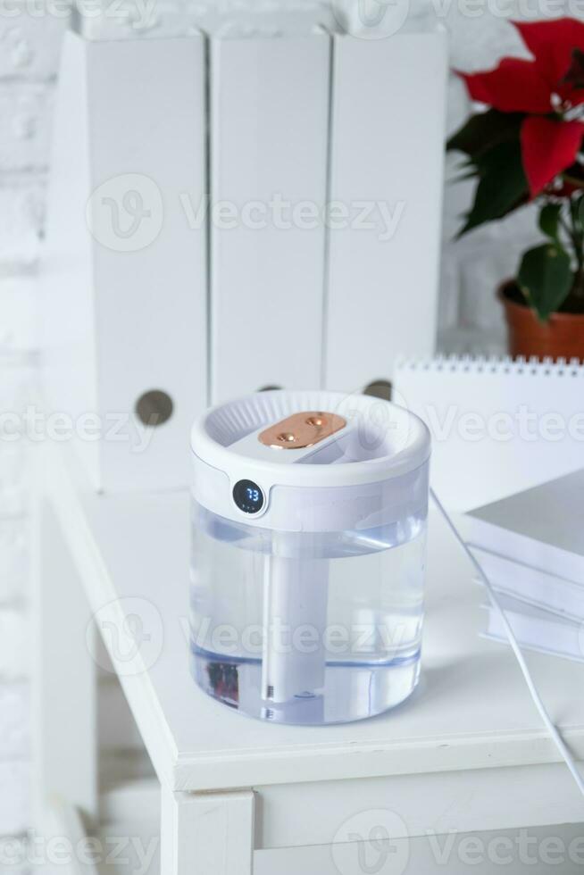 Modern air humidifier on table in living room or office . Space for text photo