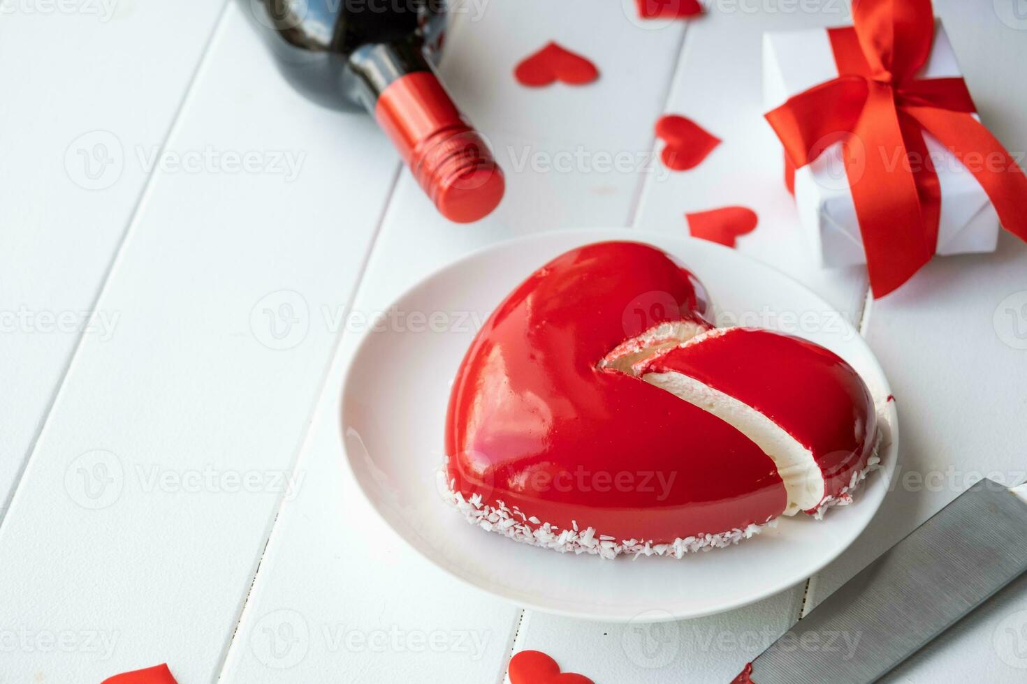 heart shaped glazed valentine cake and flowers on wooden table photo