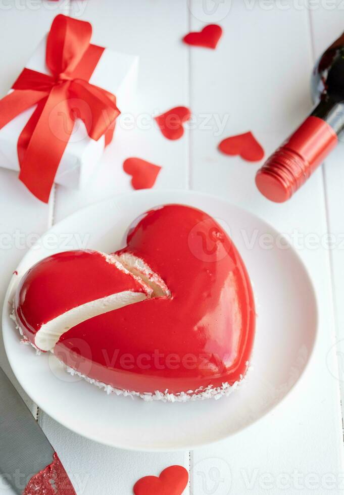 heart shaped glazed valentine cake and flowers on wooden table photo