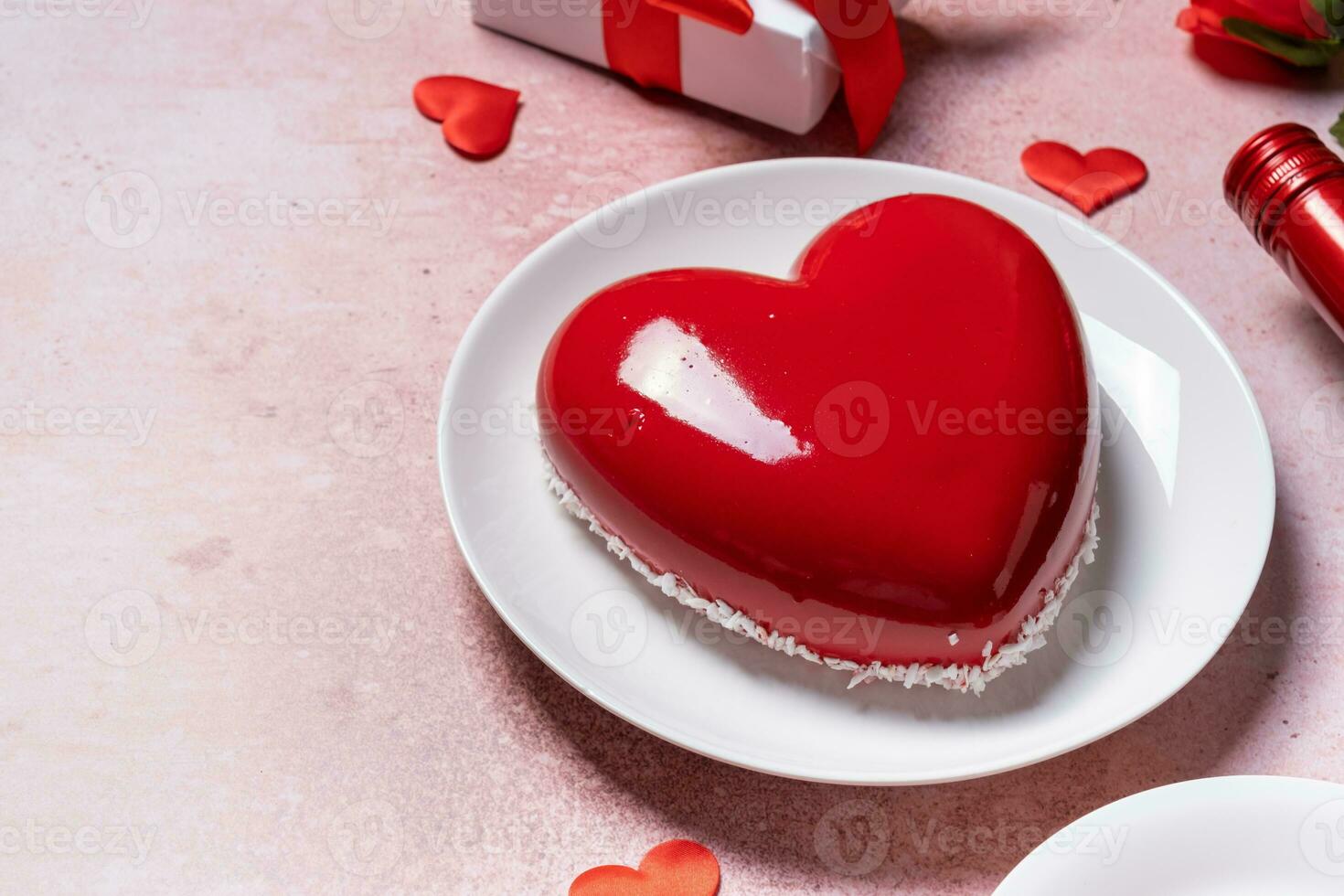 heart shaped glazed valentine cake, gift and wine on pink concrete background photo