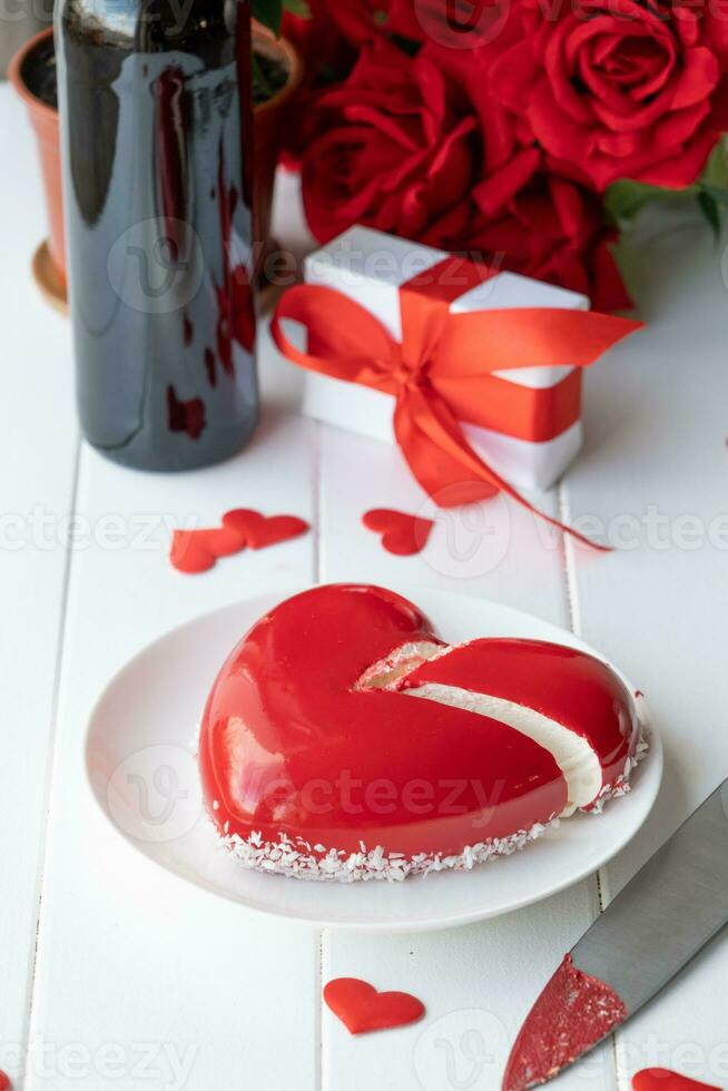 heart shaped glazed valentine cake and flowers on wooden table photo