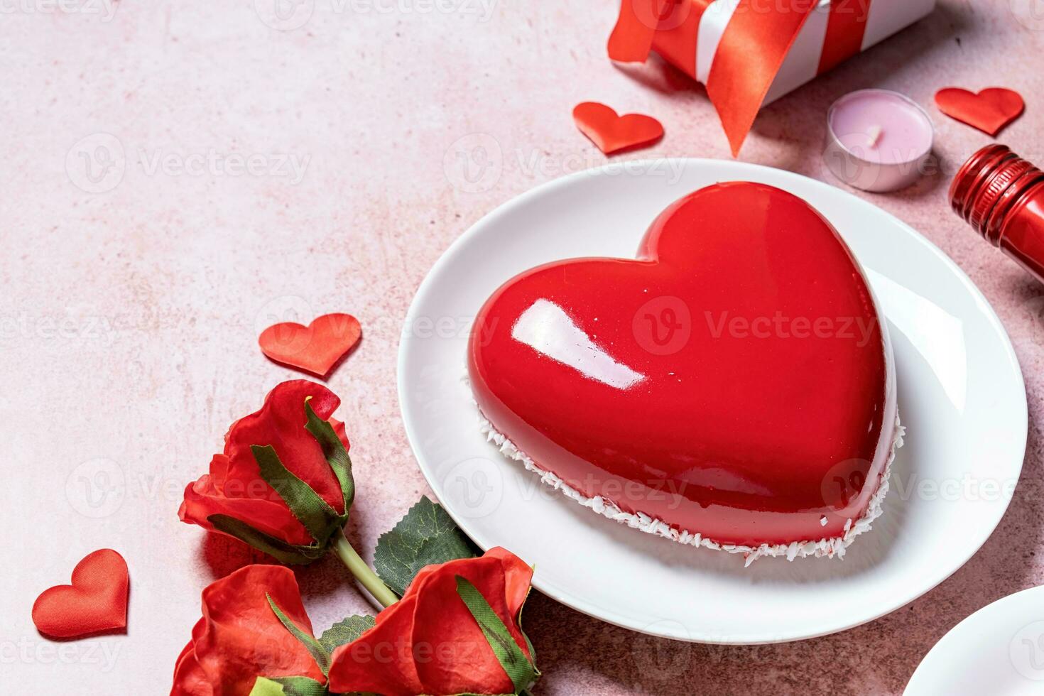 heart shaped glazed valentine cake, gift and wine on pink concrete background photo