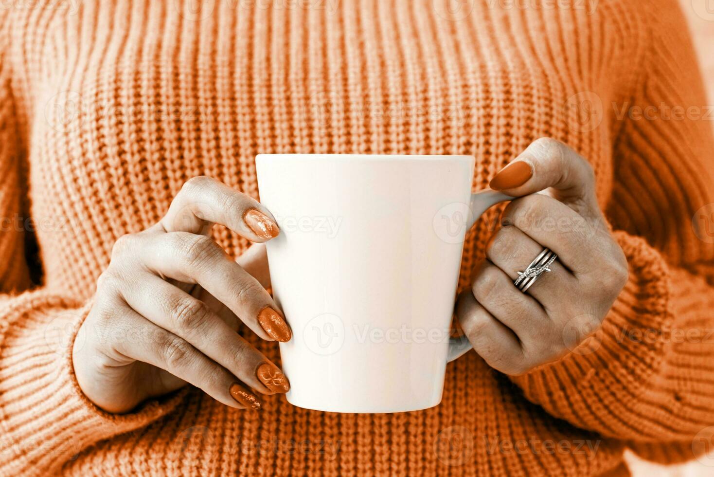 Color of the year 2024, Peach Fuzz. closeup woman hands holding white mug for mockup design photo