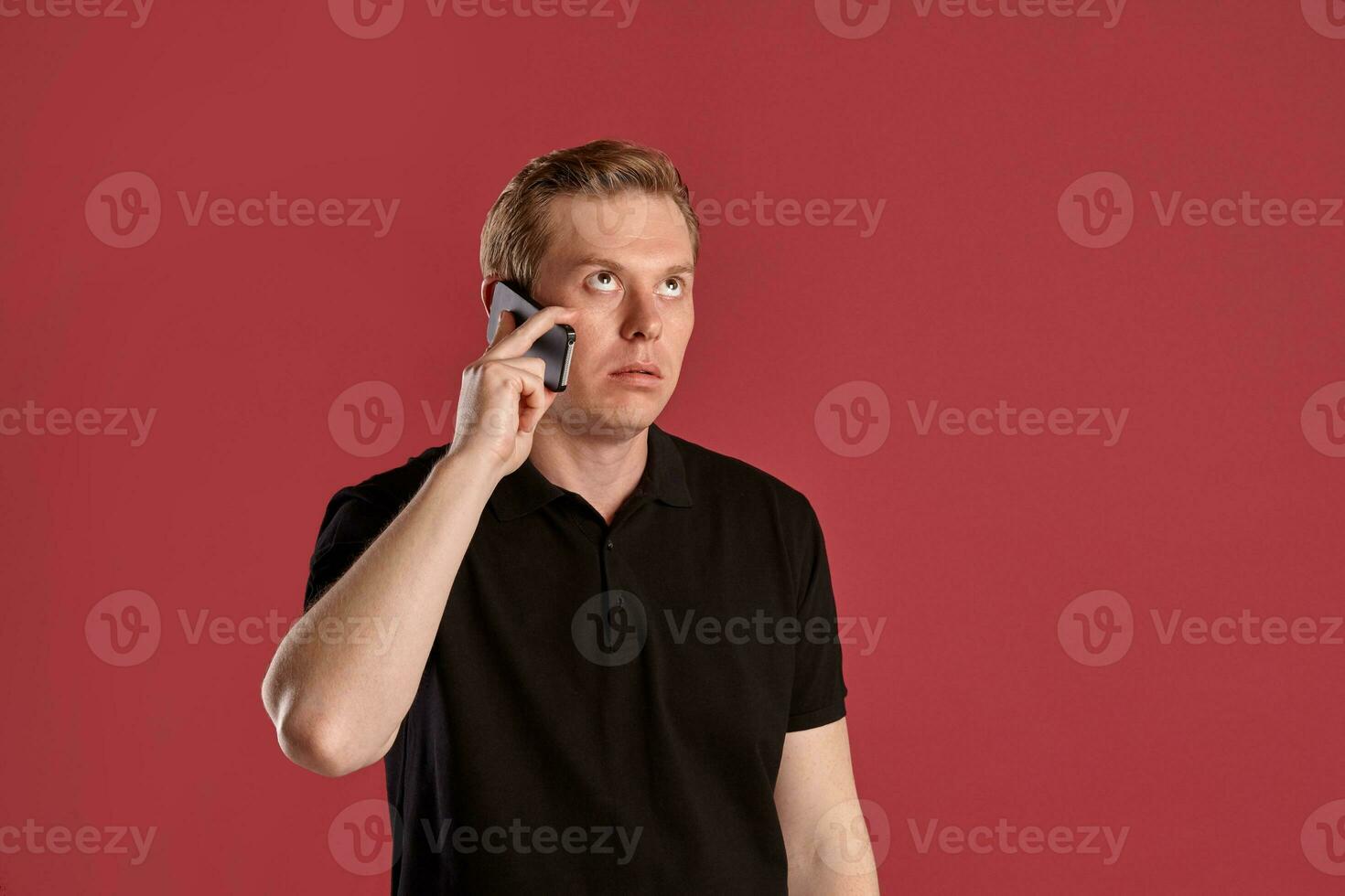 Close-up portrait of a ginger guy in black t-shirt posing on pink background. Sincere emotions. photo