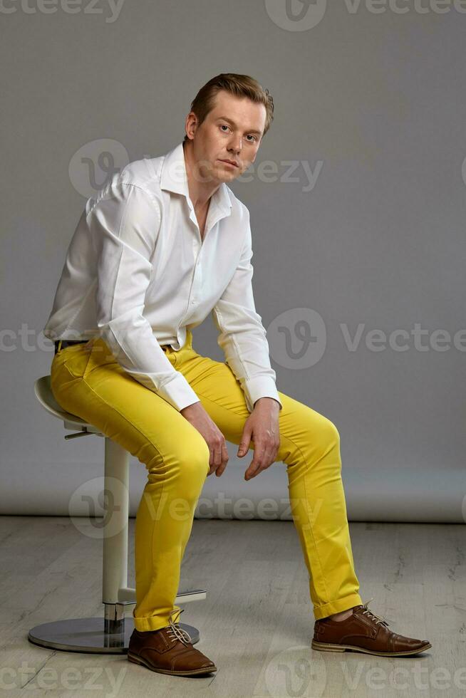 Full length portrait of a ginger guy in white shirt posing on gray background. Sincere emotions. photo