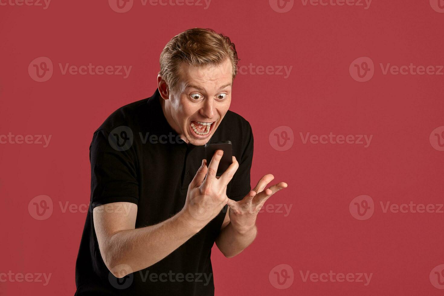 Close-up portrait of a ginger guy in black t-shirt posing on pink background. Sincere emotions. photo