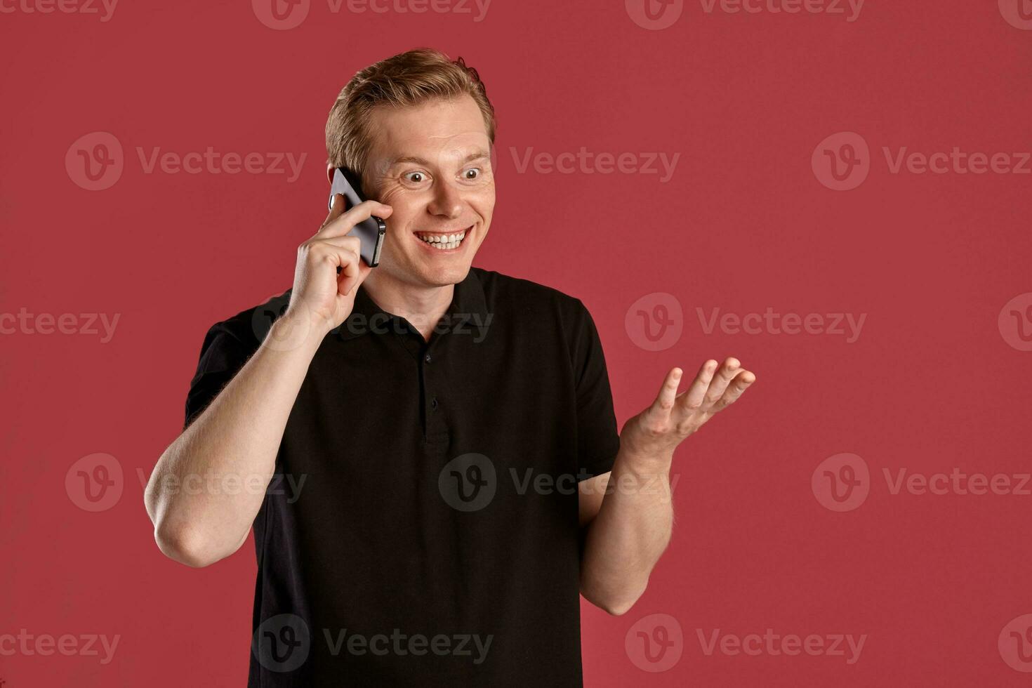 Close-up portrait of a ginger guy in black t-shirt posing on pink background. Sincere emotions. photo