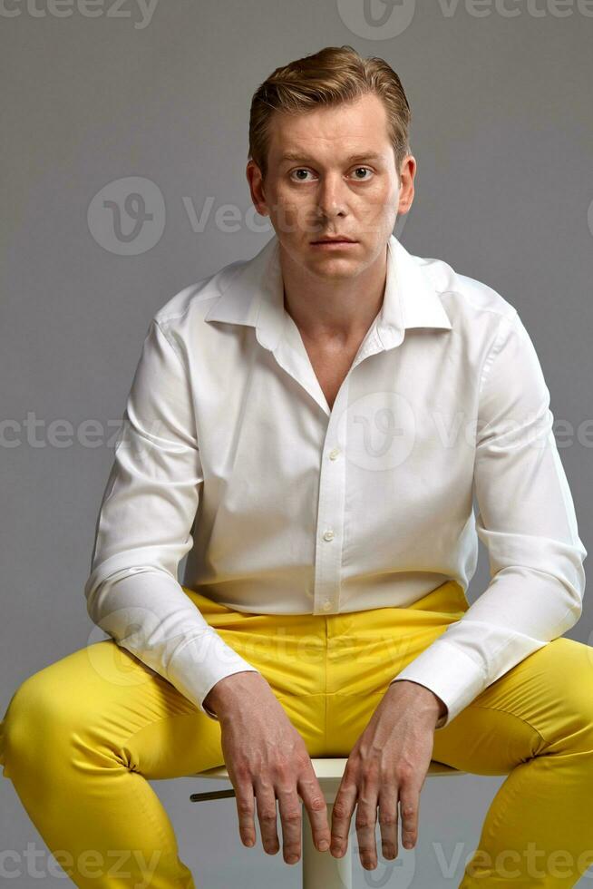 Close-up portrait of a ginger guy in white shirt posing on gray background. Sincere emotions. photo