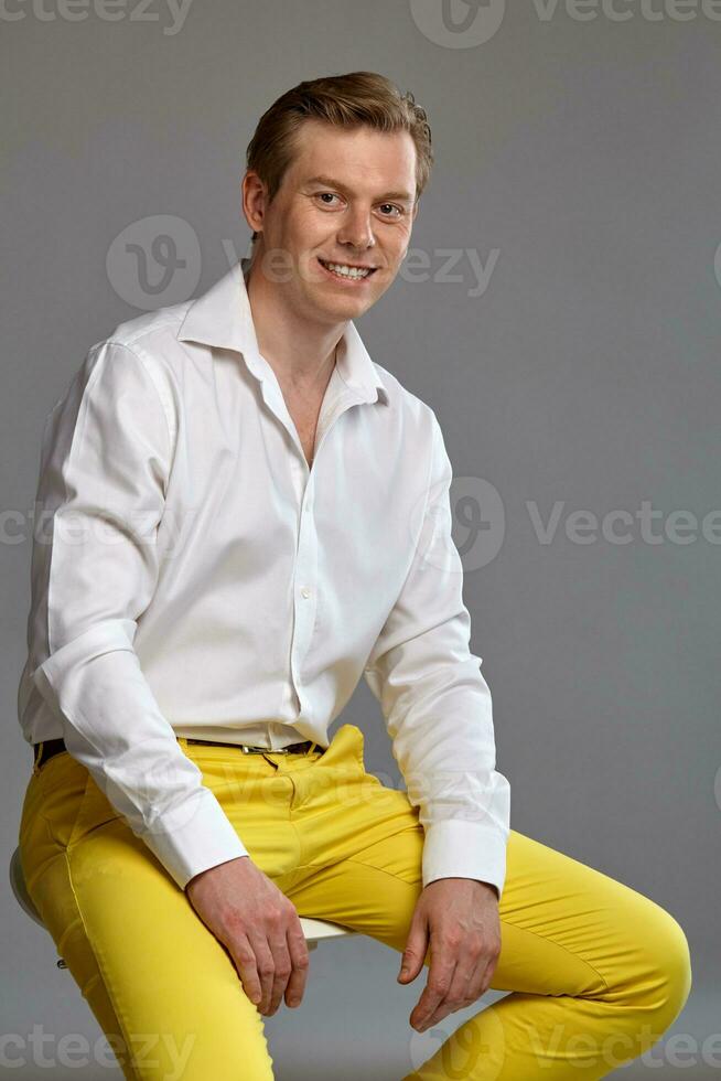 Close-up portrait of a ginger guy in white shirt posing on gray background. Sincere emotions. photo