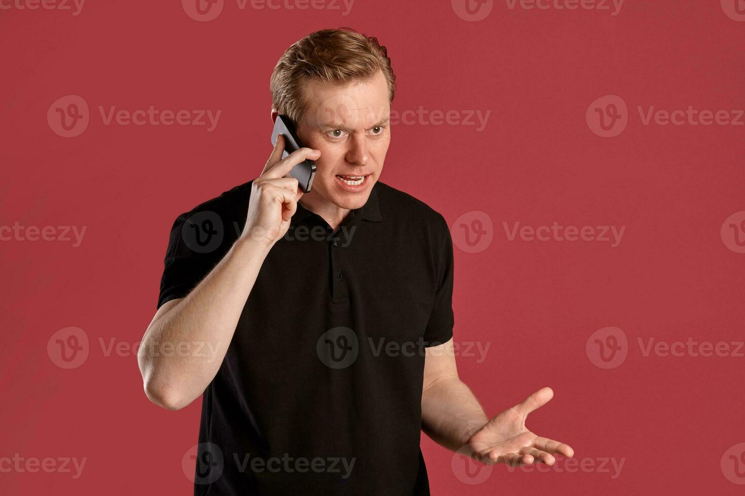 de cerca retrato de un jengibre chico en negro camiseta posando en rosado antecedentes. sincero emociones foto