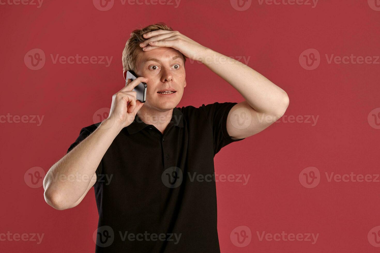 de cerca retrato de un jengibre chico en negro camiseta posando en rosado antecedentes. sincero emociones foto