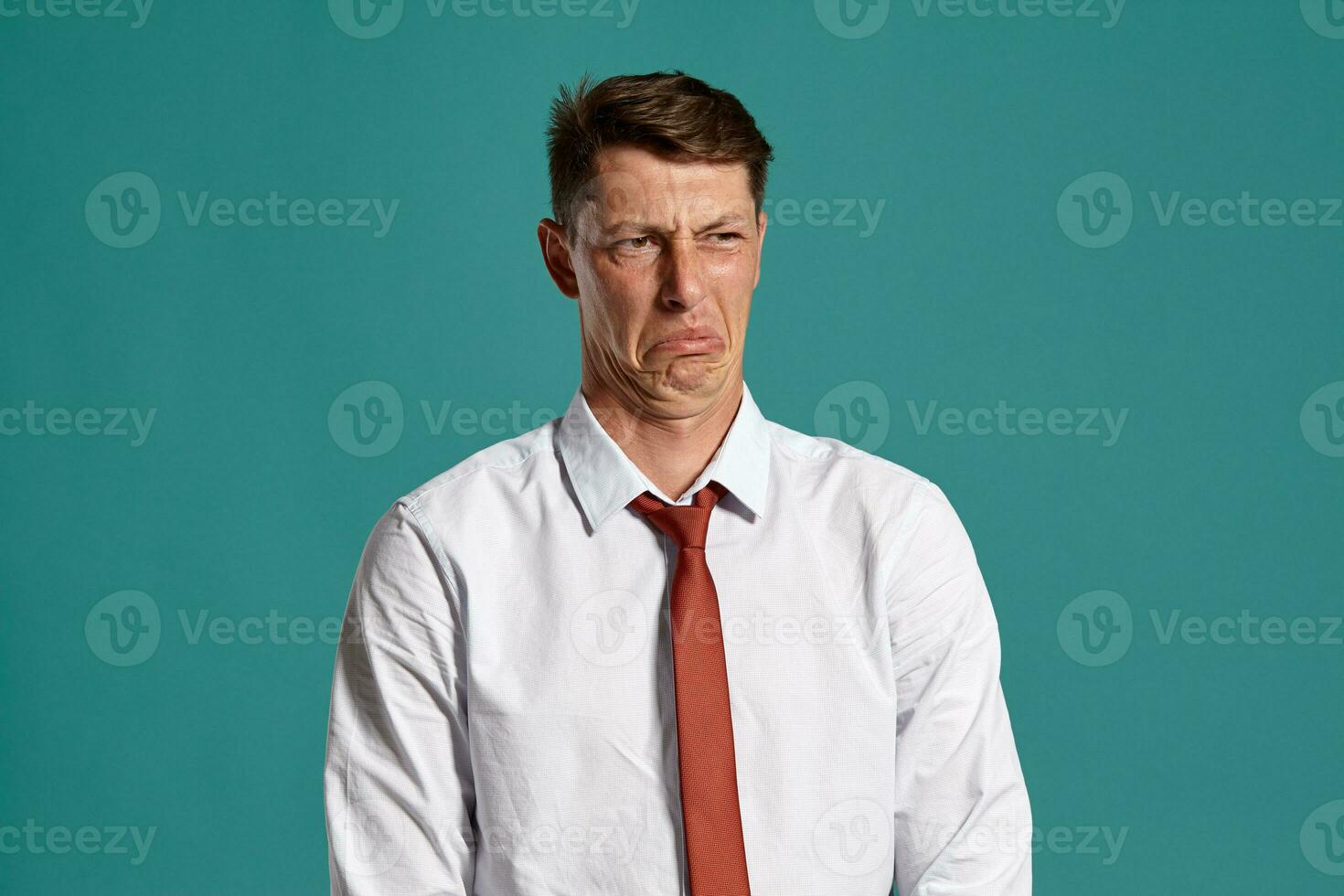 Portrait of a young brunet man posing in a studio against a blue background. photo