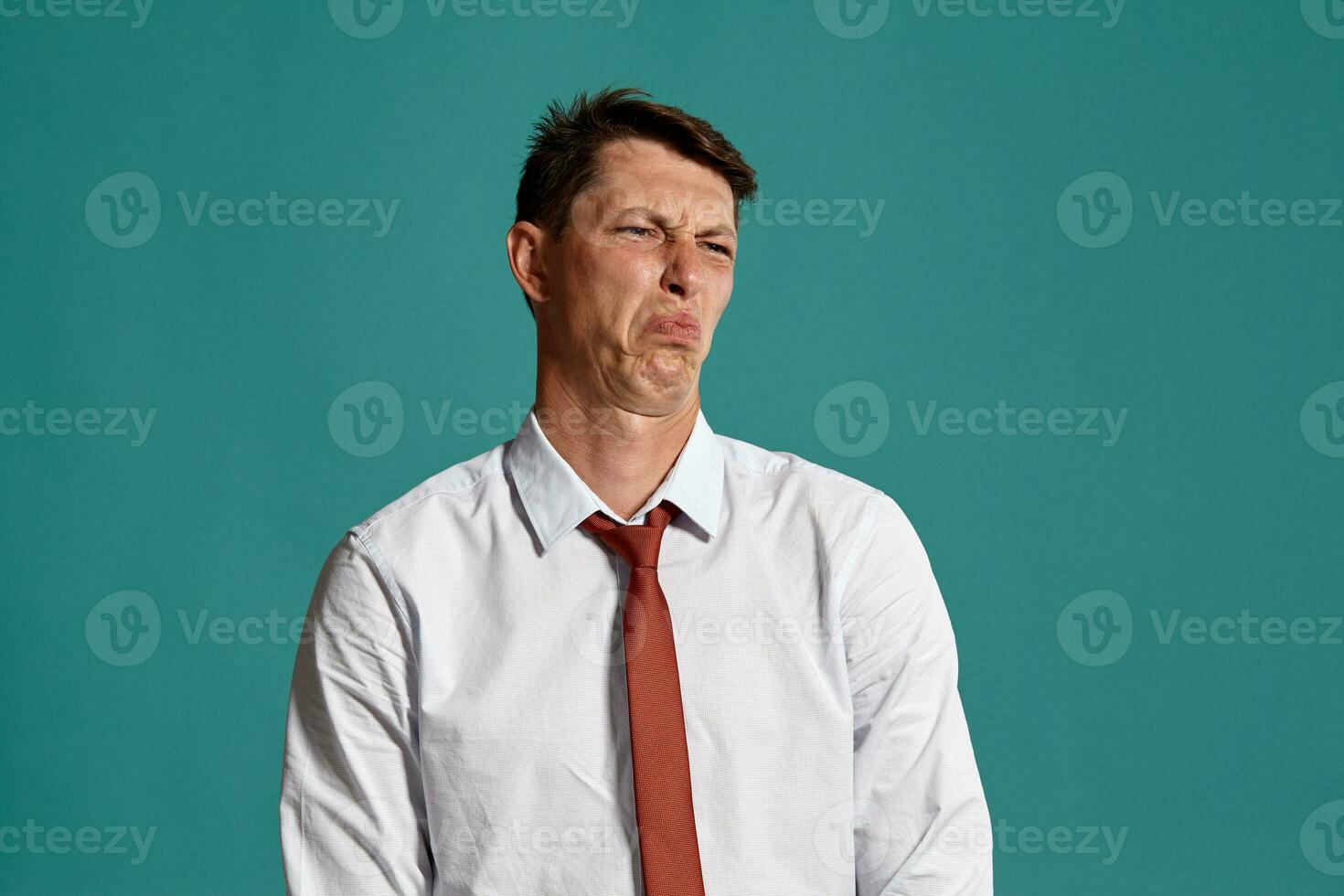 Young man in a classic white shirt and red tie posing over a blue background. photo