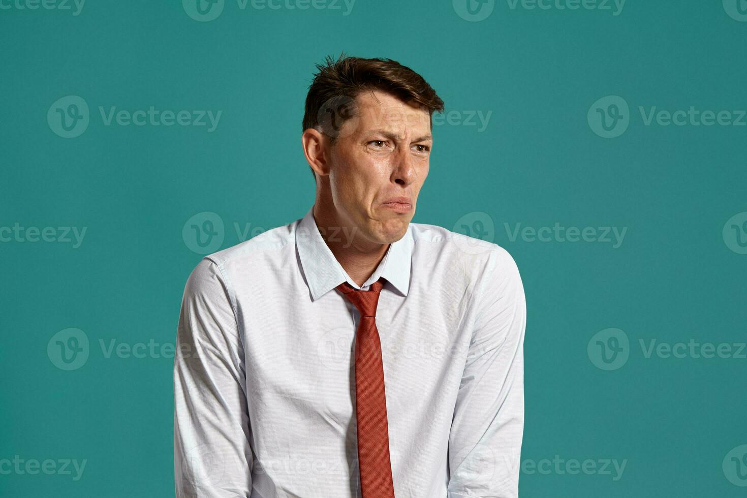 Young man in a classic white shirt and red tie posing over a blue background. photo