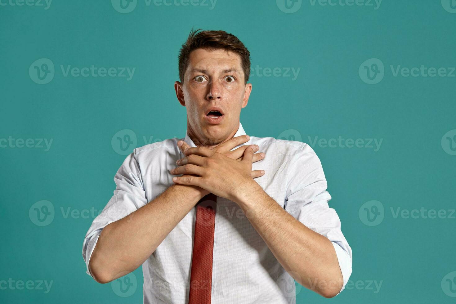 Young man in a classic white shirt and red tie posing over a blue background. photo