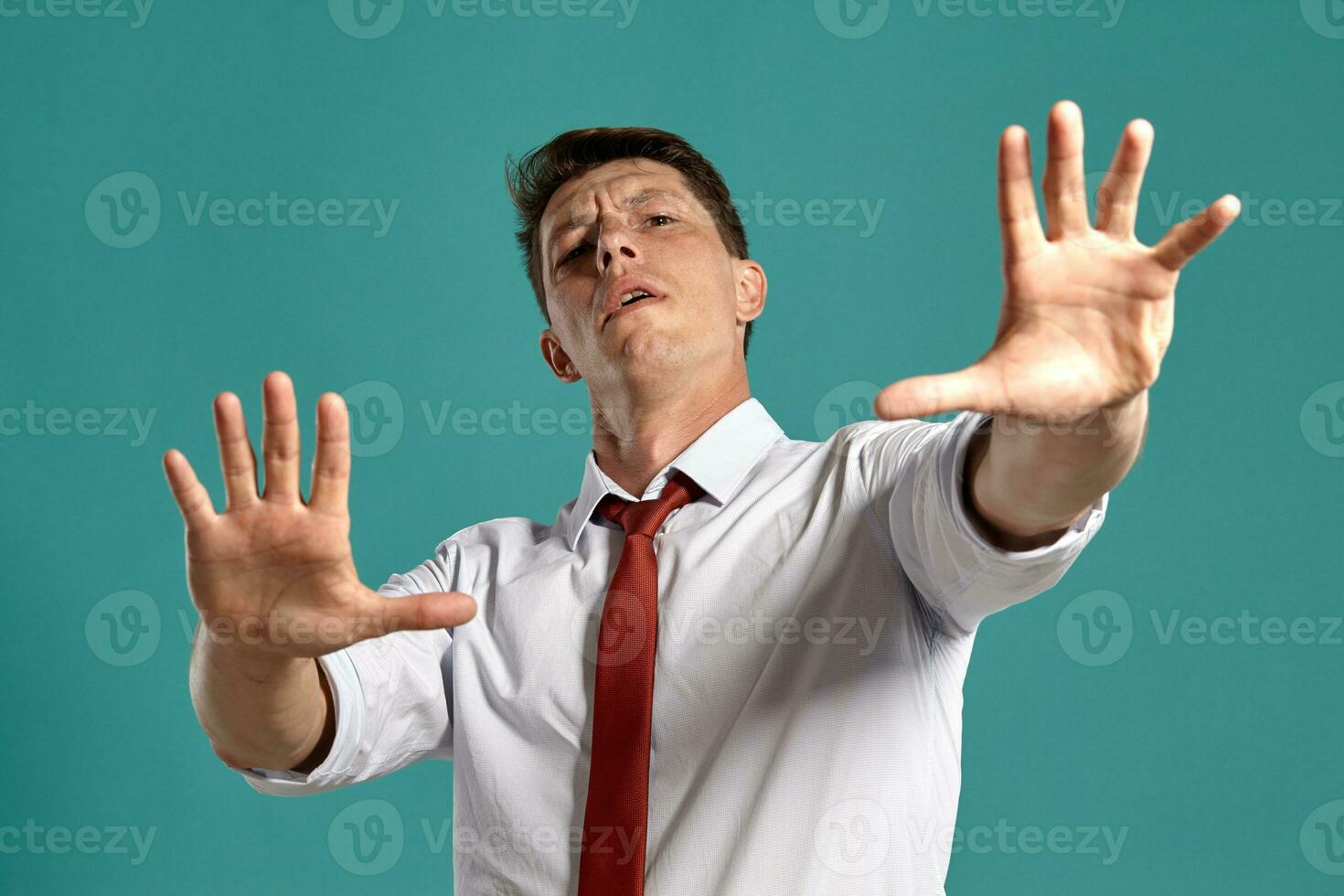 Young man in a classic white shirt and red tie posing over a blue background. photo