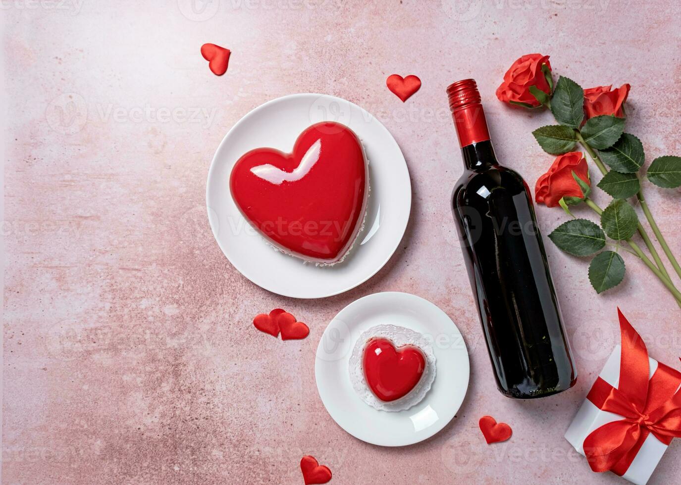 heart shaped glazed valentine cake, gift and wine on pink concrete background photo