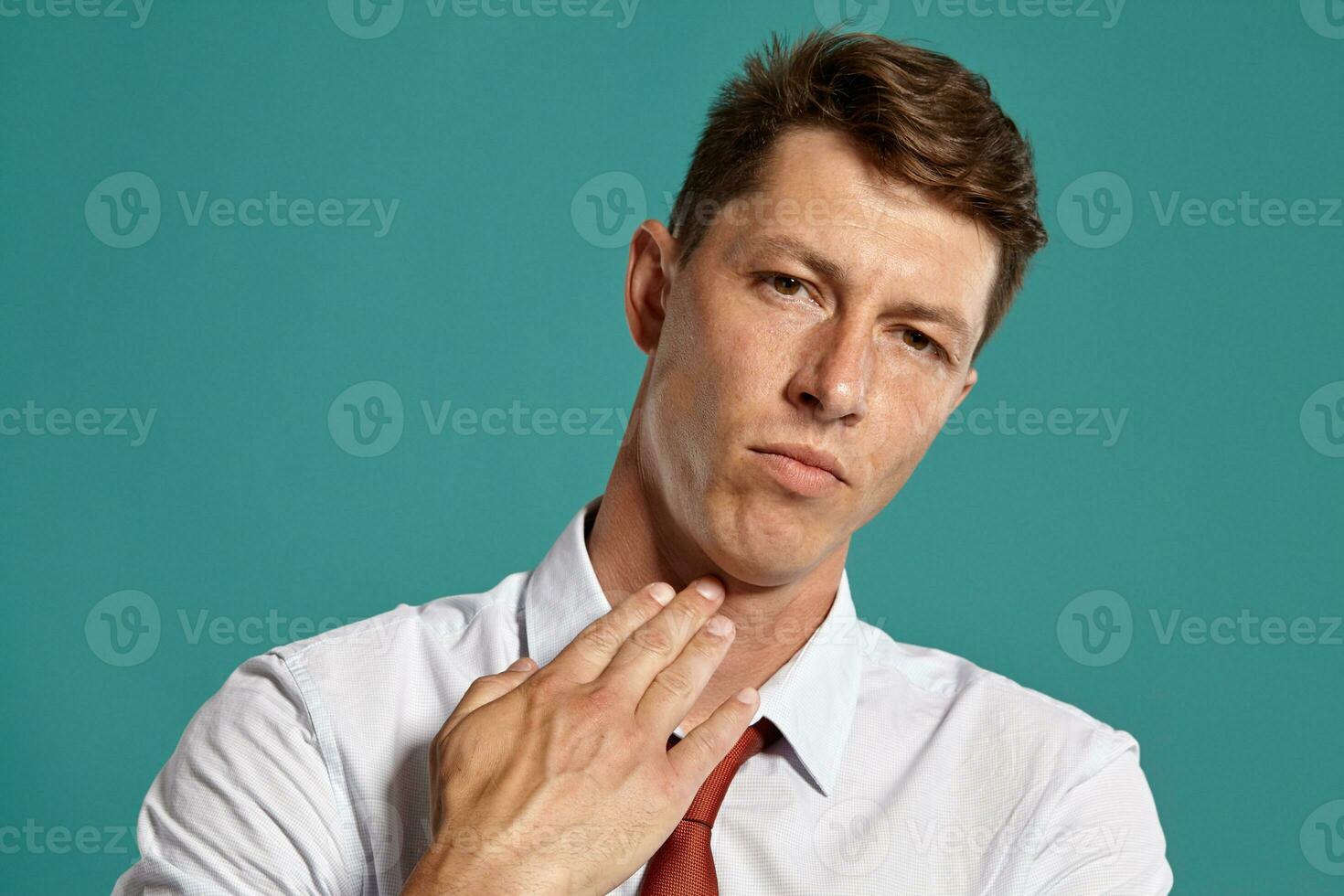 Portrait of a young brunet man posing in a studio against a blue background. photo