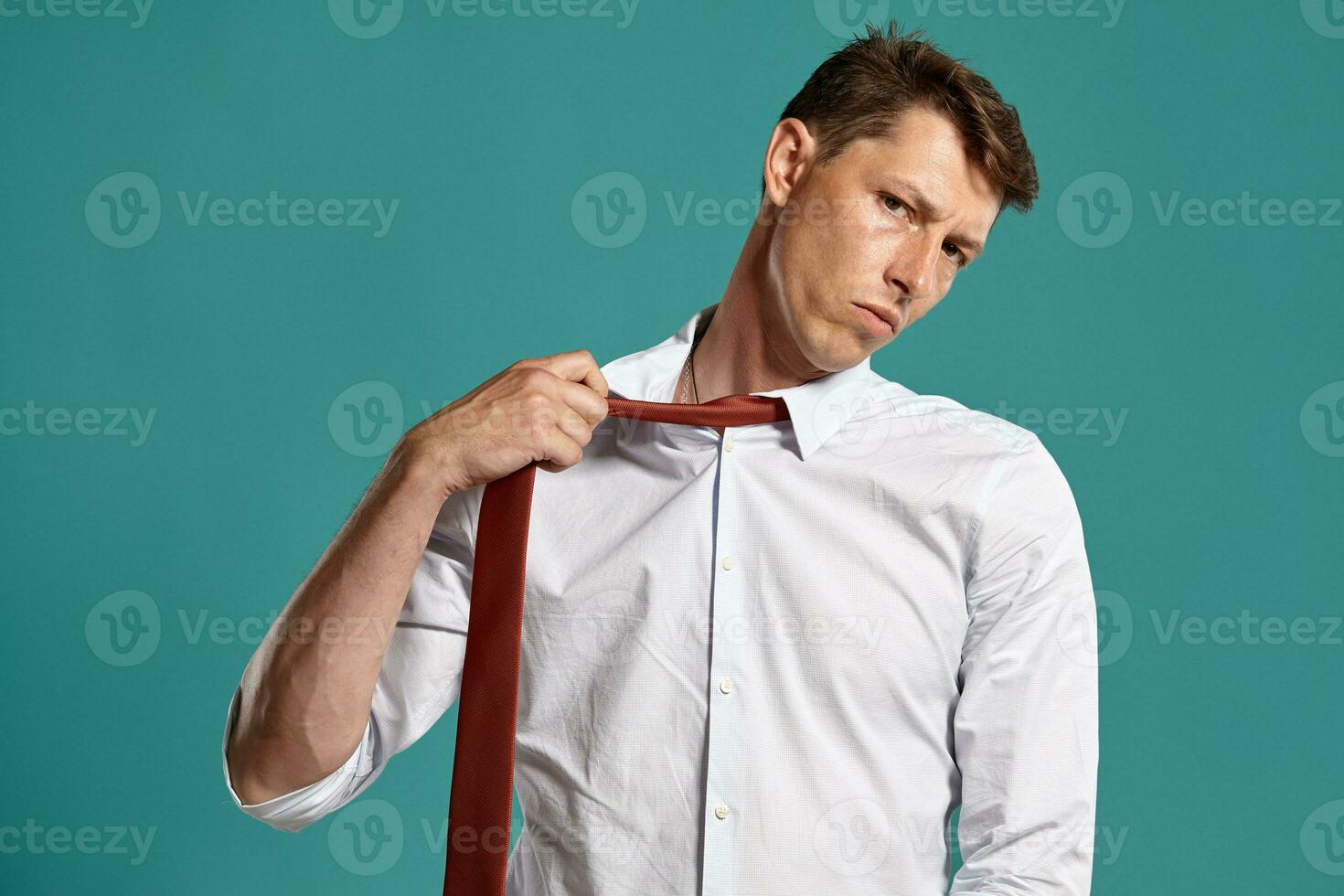 Portrait of a young brunet man posing in a studio against a blue background. photo