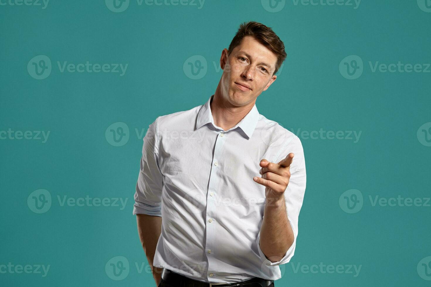 Young man in a classic white shirt is posing over a blue background. photo