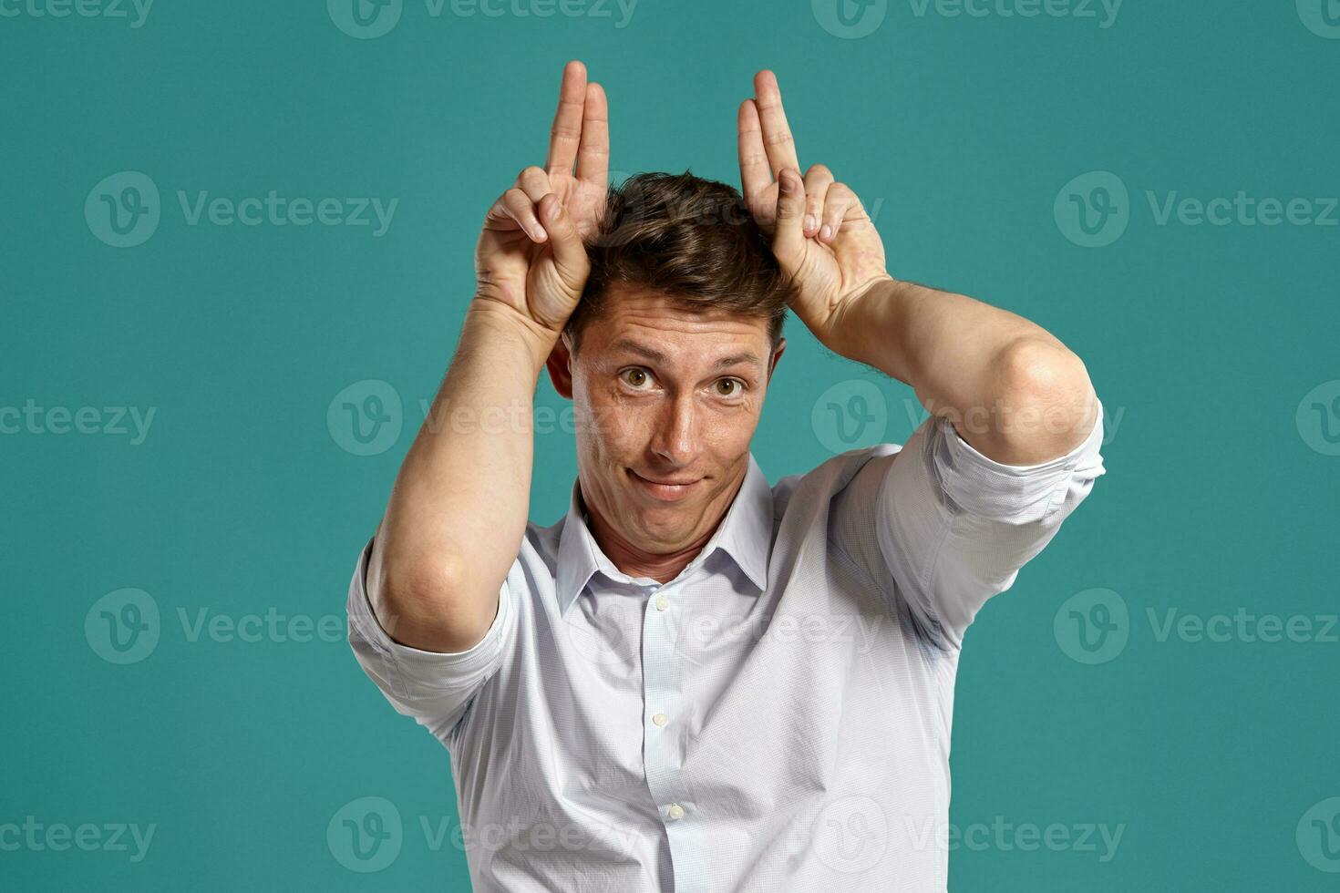 Young man in a classic white shirt is posing over a blue background. photo