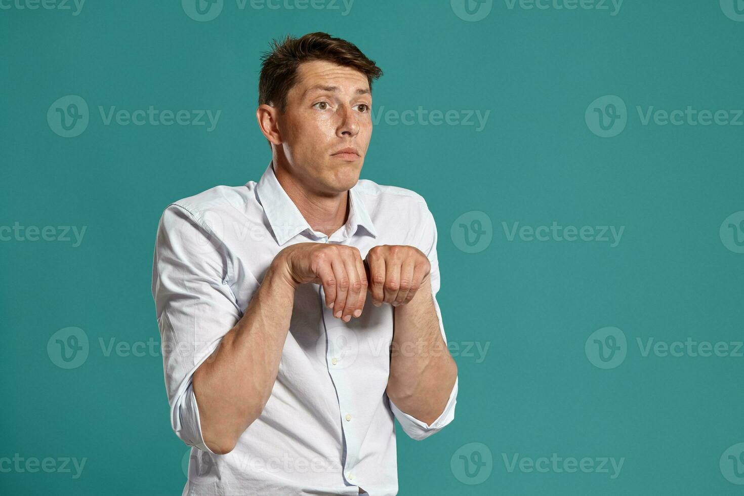 Young man in a classic white shirt is posing over a blue background. photo