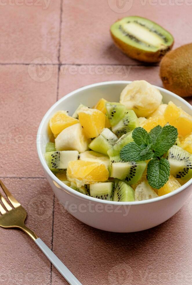 Bowl of healthy fresh fruit salad on ceramic background photo